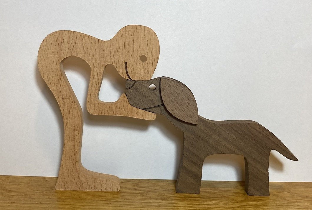Sculpture en bois de couleur naturelle et marron représentant une personne et un chien s'embrassant. Décoration artisanale.